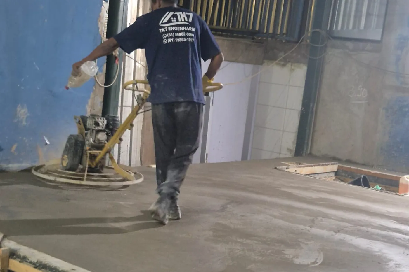 Profissional da TK7 Engenharia acabando um piso de concreto com acabadora mecânica