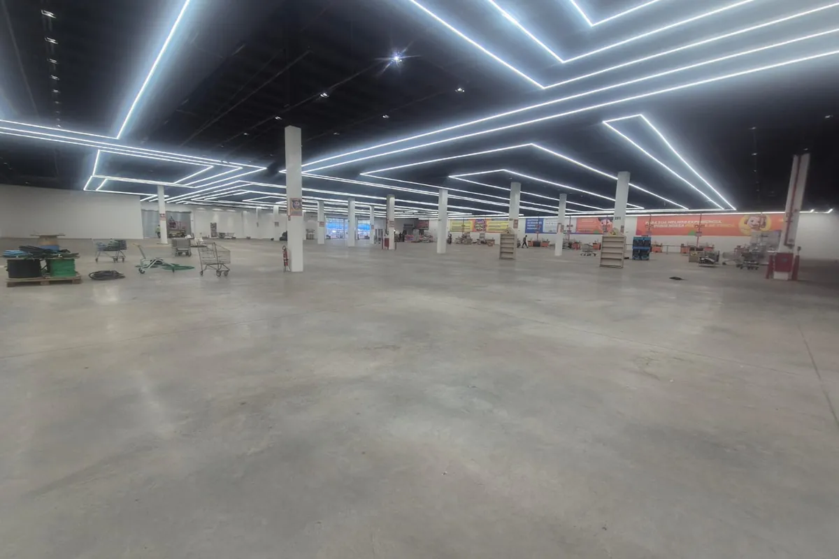 Área de vendas ampla com piso de concreto polido sob iluminação linear